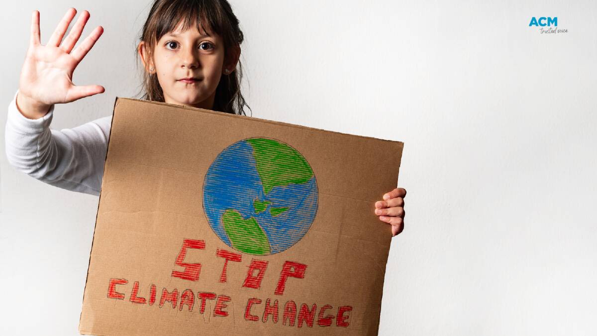 A young girl holds a hand drawn sign reading "stop climate change". Picture via Canva