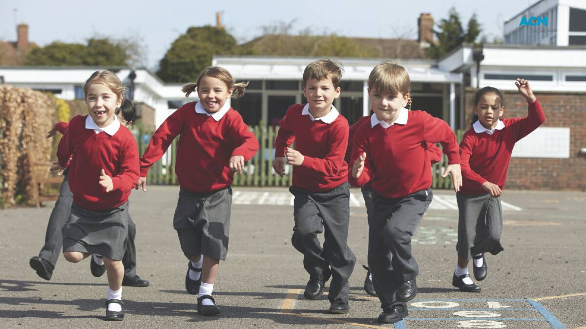 Young children in school uniforms run towards the camera. File picture