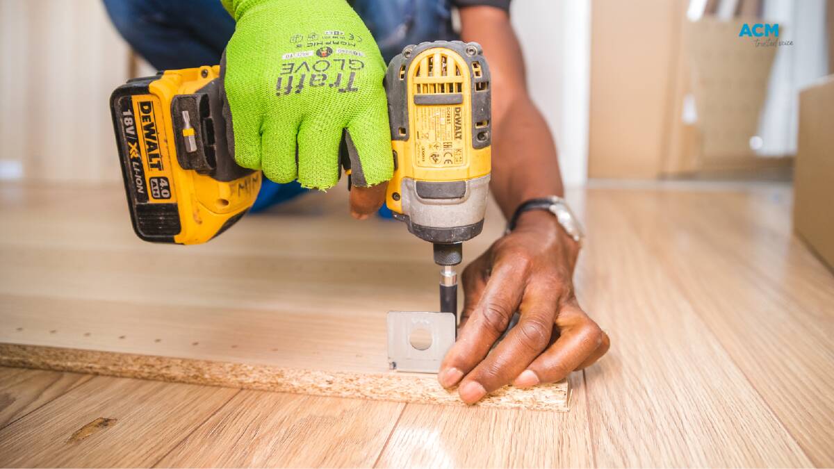 A builder drills into a floorboard. Picture by Bidvine via Canva