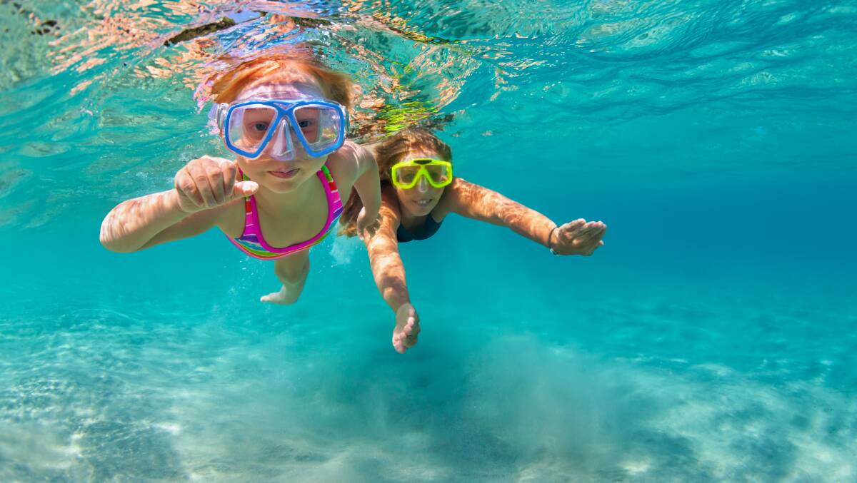 Two young women swim in snorkels and vibrantly patterned swimwear. Picture by Shutterstock.