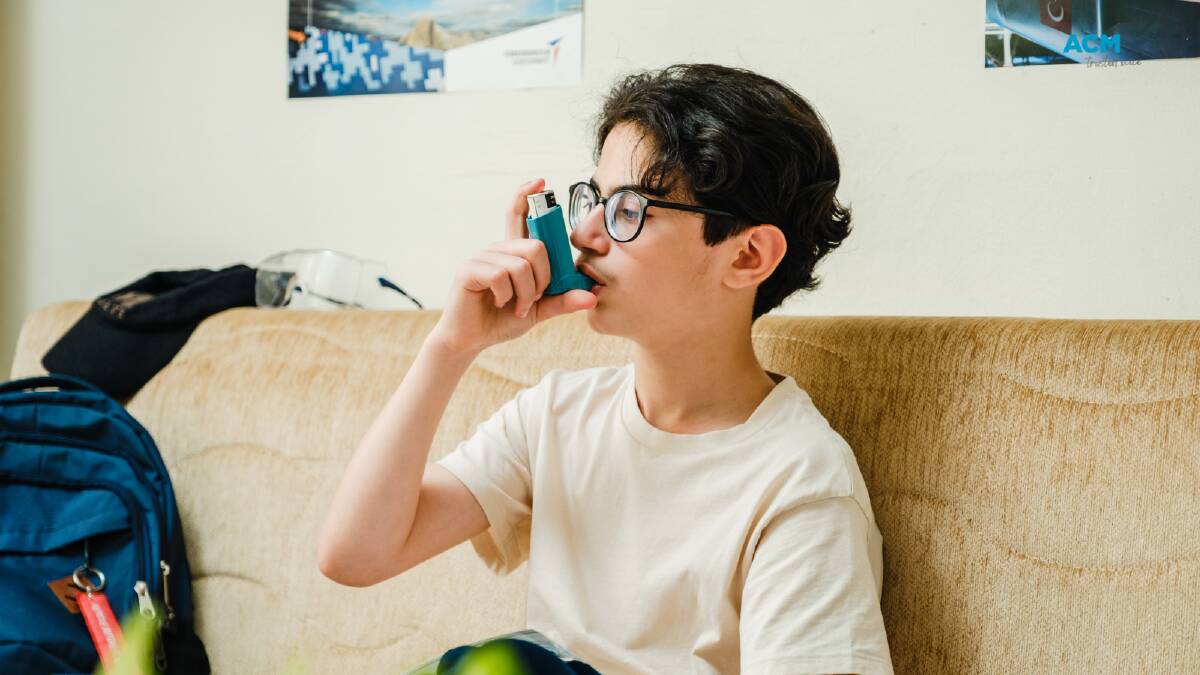 A child uses an asthma inhaler while sitting on a couch. File picture. 
