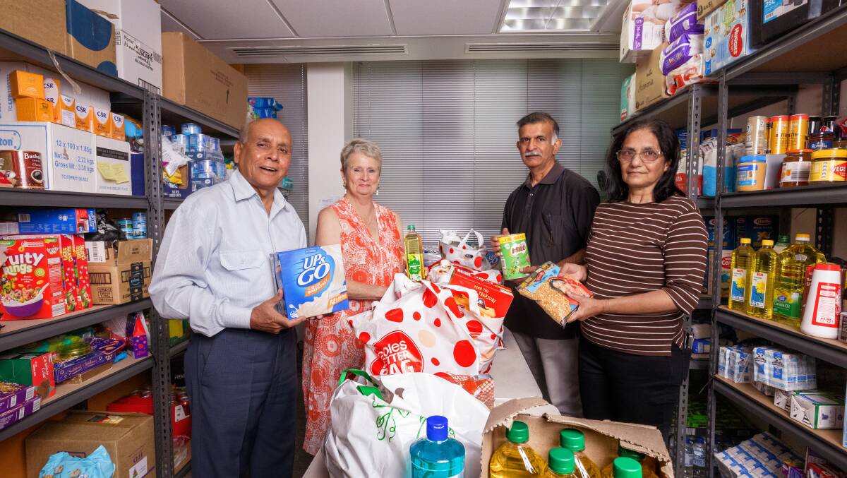 Mohammed Ali and volunteers Toni La Brooy, and Sainath and Devyabi Mallapur pack groceries at Helping ACT headquarters. Picture by Sitthixay Ditthavong 