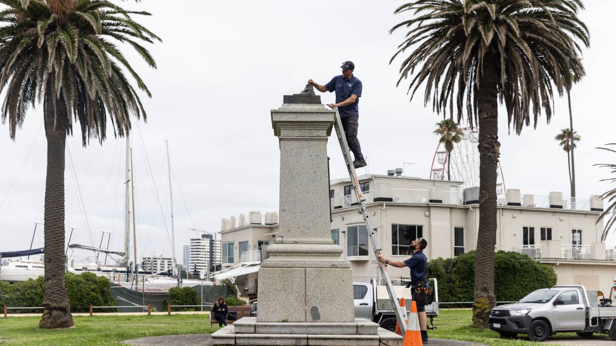 Workers inspect the Captain Cook statue in St Kilda after it was sawn off at the ankles on January 25. Picture by AAP Image/Diego Fedele