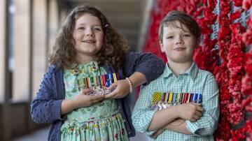 Mathilda Berry, 8 and brother Lucas, 6, hold aloft their family's war medals. Picture by Gary Ramage