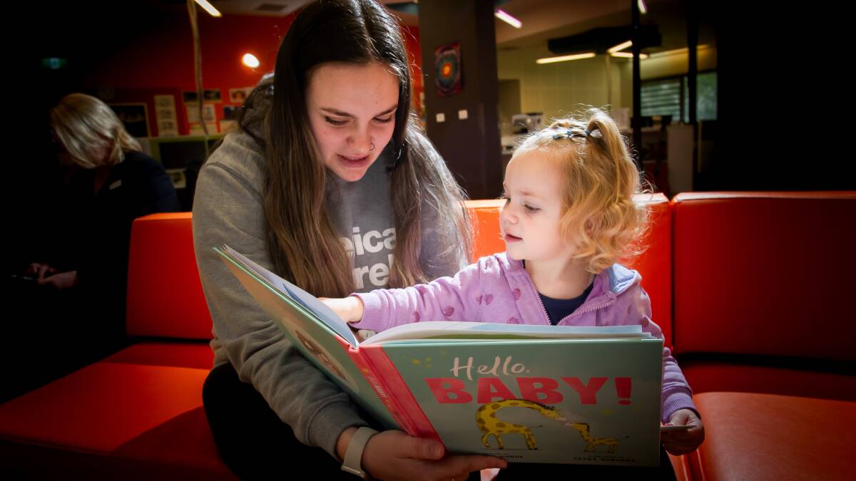 Kaylee Johnson, 21, reads to daughter Skylah Stefanoski, 2, on International Literacy Day at Canberra College Cares. Picture by Elesa Kurtz