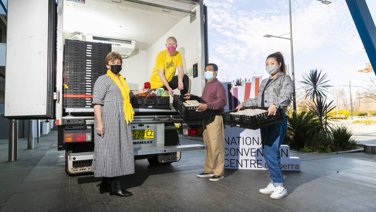 OzHarvest Canberra City manager Bin Barnier and driver Aaron McNeil collect cooked meals on Friday from the National Convention Centre's Halim Othman and Thi Nguyen. Picture: Keegan Carroll
