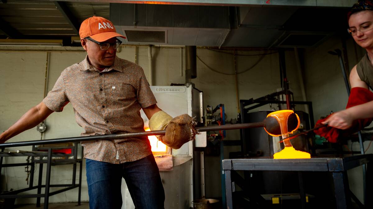 Dr Jeffrey Sarmiento, head of the ANU Glass Workshop demonstrates how the trophies start as molten glass. Picture by Elesa Kurtz