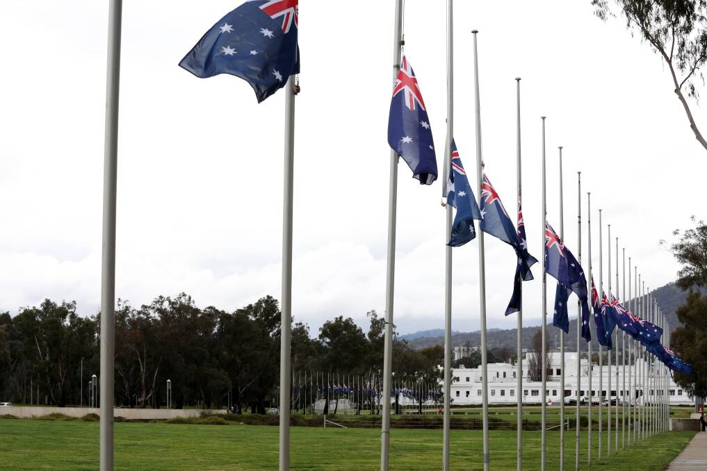 Flags at half-mast between Old Parliament House and Parliament House on Friday. Picture by James Croucher