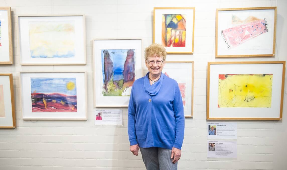 Wendy Pearse, 77, of Kingston with her work (at left) at the Painting with Parkinsons exhibition on Friday. Picture by Karleen Minney