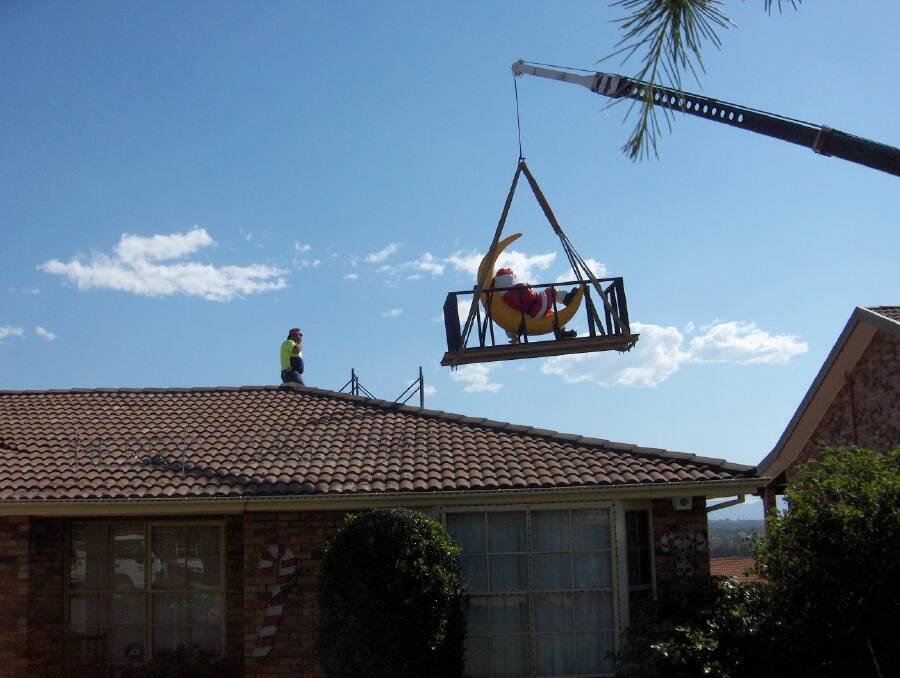 A crane lifts the fibreglass Santa into place at the Smiths' home in McKellar in 2006. Picture: Phillip Smith