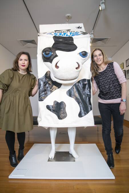 Canberra Museum and Gallery social history curator Tiaan Zampaglione and senior social history curator Sharon Bulkeley (far left) with an old Canberra Milk mascot. Picture: Keegan Carroll