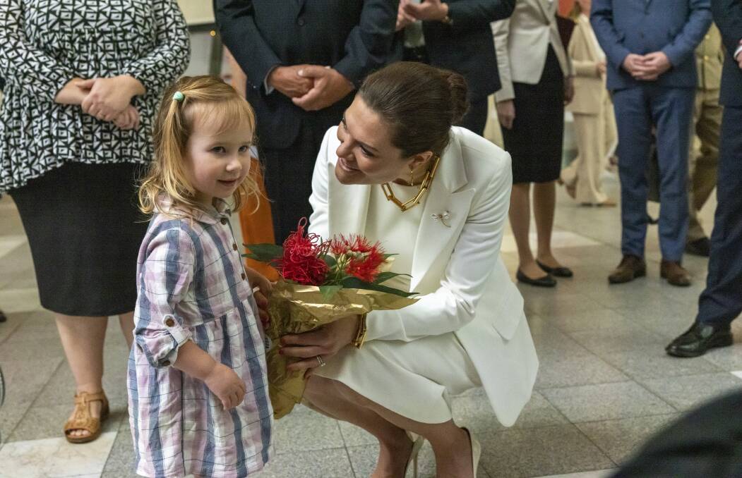 Sweden's Crown Princess Victoria accepts a bunch of native flowers from Bonnie Heap, 2, of Ngunnawal. Picture by Keegan Carroll