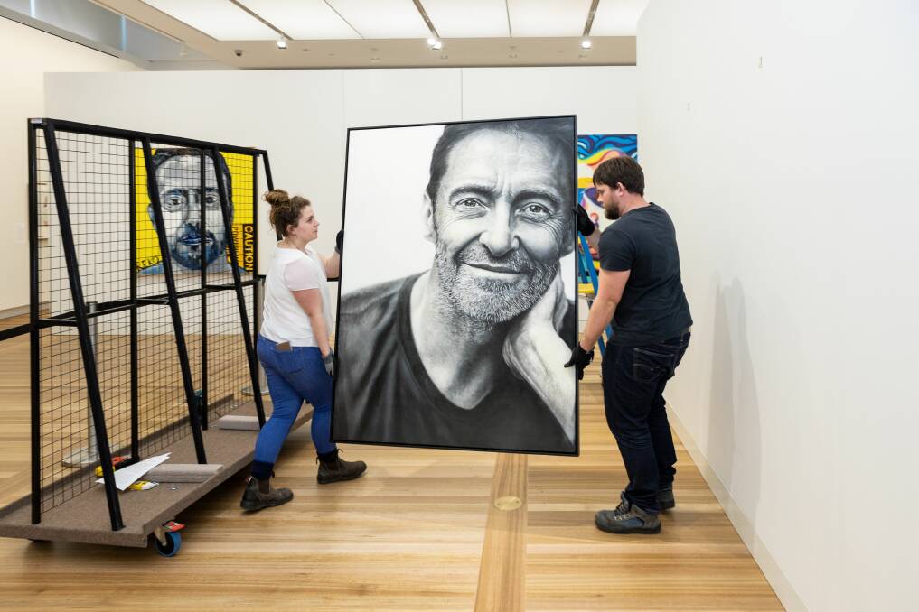  The new portrait being put in place at the National Portrait Gallery by Jessica Kemister and James Ley.Picture: Mark Mohell