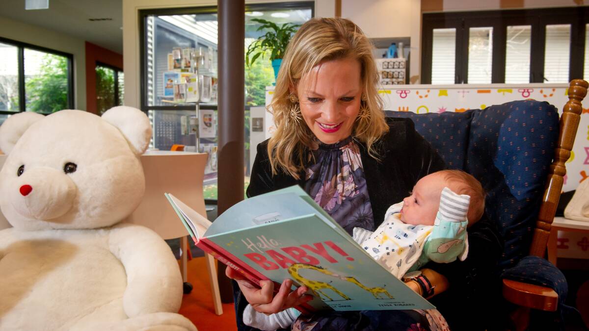 Canberra author Shelly Unwin reads her book Hello Baby! to one of the student's babies, Taylem Fort, three months, at Canberra College Cares. Picture by Elesa Kurtz