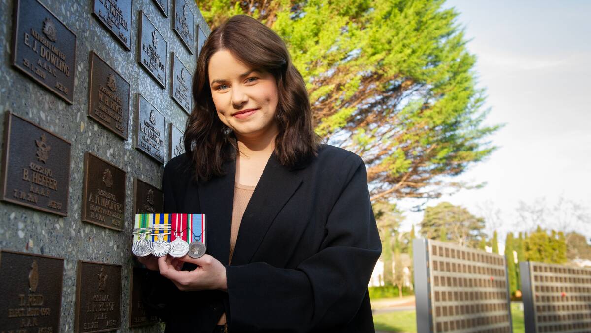 Kate MacInnes with her father's medals at a plaque for him in the military section of the Woden cemetery. Picture by Elesa Kurtz