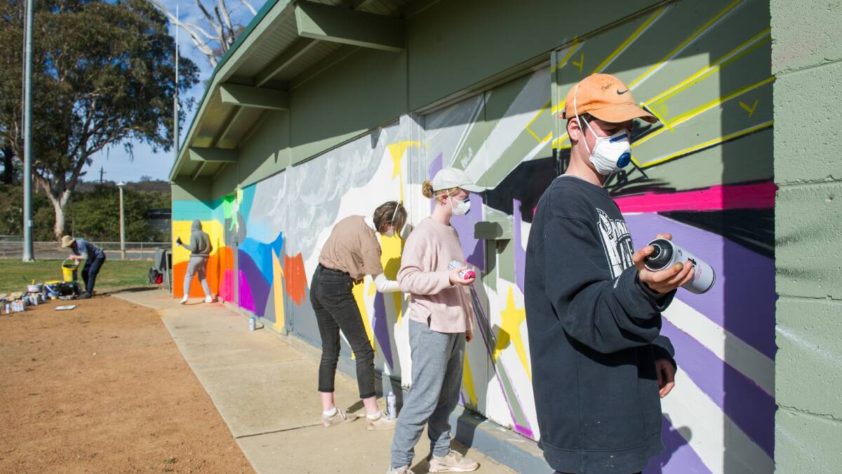 Senior students at the Blue Gum Community School in 2019 helping to paint the mural at the Hackett Oval which they also helped to design. Picture by Elesa Kurtz