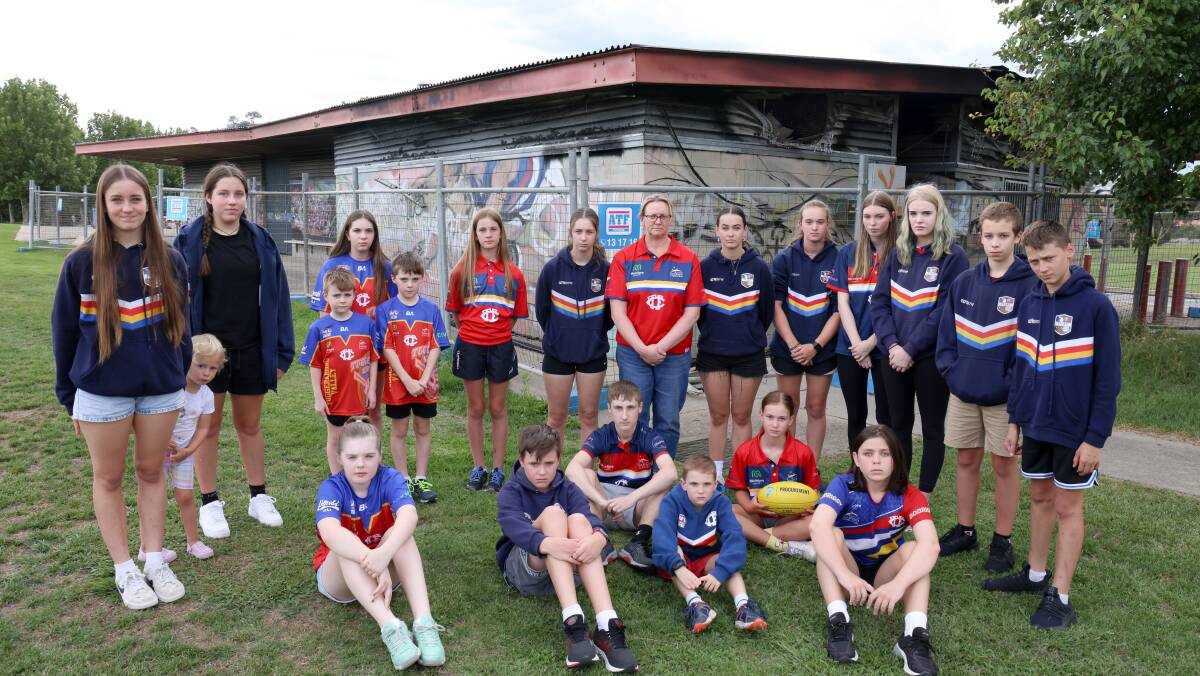 Tuggeranong Valley Australian Football Netball Club president Kellie Hogan (centre) with some of the junior players and the burnt-out shed at Gordon. Picture by James Croucher