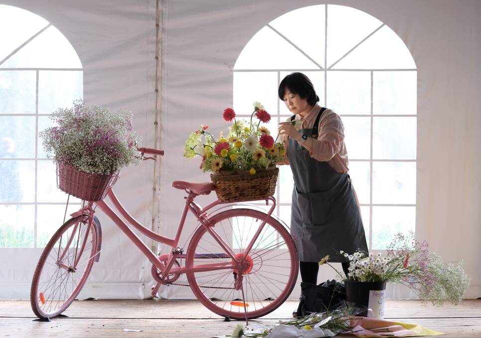 CIT floristry student Jihee Hwang puting together a display at Floriade. Picture by James Croucher