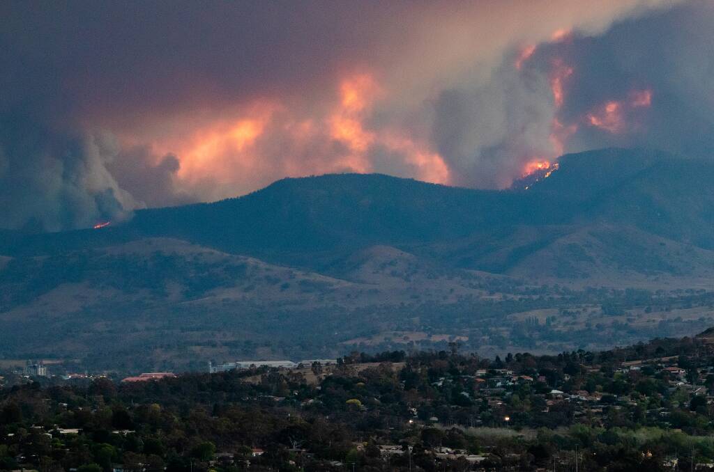 Fire comes over the ridge behind Tuggeranong on Tuesday afternoon. Picture: Adam Spence