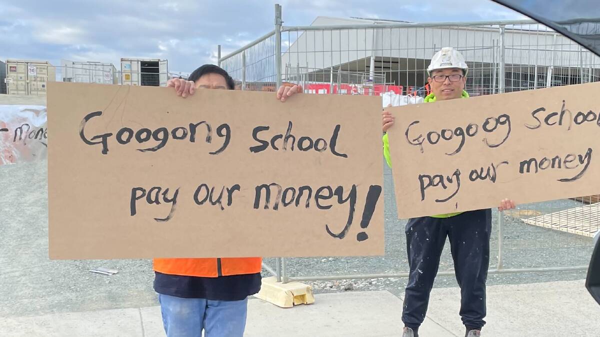 A group of construction workers held signs outside the Googong Public School site on Monday morning. Picture supplied