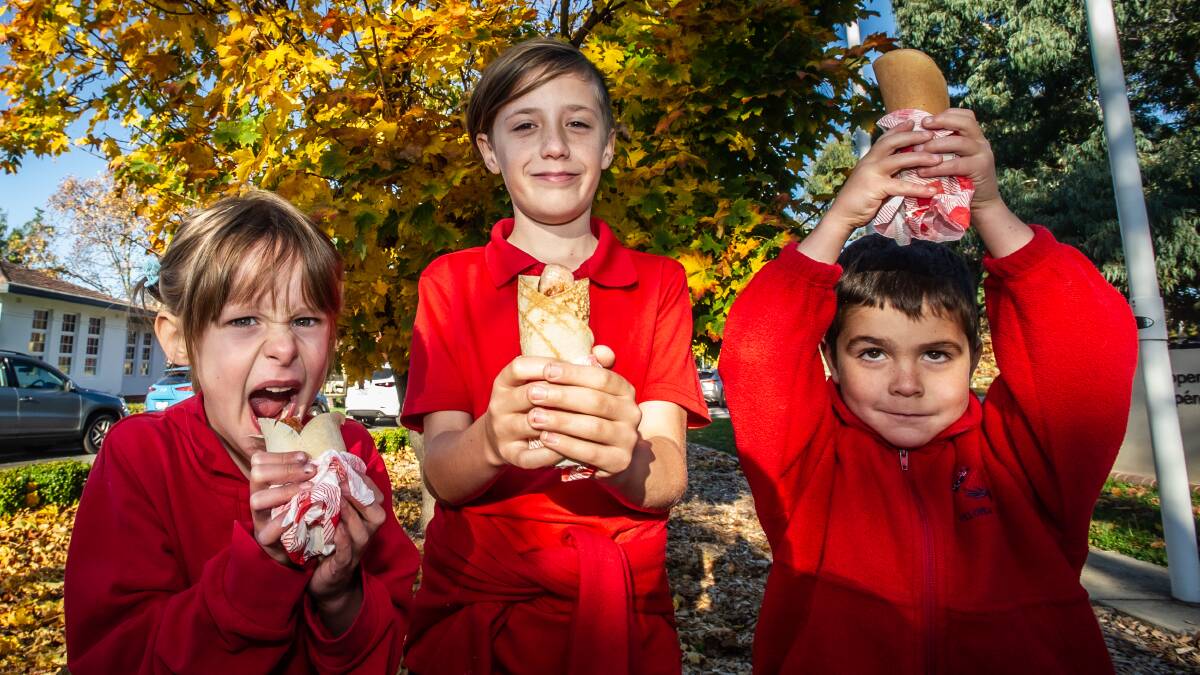 Telopea Park School students Olympia and Luther Griffin and Romeo Foulcher sample the galette-saucisse, a French-style democracy sausage which will be on offer on election day. Picture: Karleen Minney