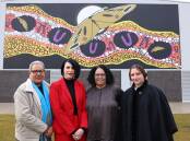 Evelyn Scott School principal Jackie Vaughan (second from left), and Charmaene, Katherine and Kristine Scott stand in front of a mural by Lynnice Church. Picture: James Croucher