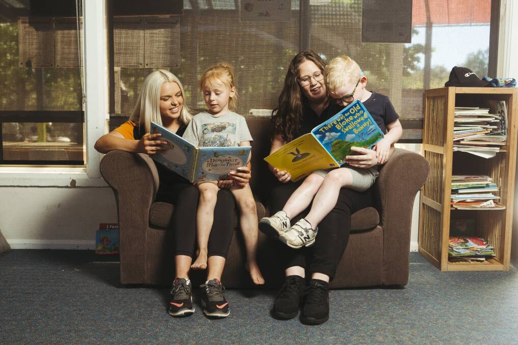 Infant team leader Kelly Adams and educator Bec Leader reading books to Lara Shepard and William Kalsbeek. Picture: Dion Georgopoulos