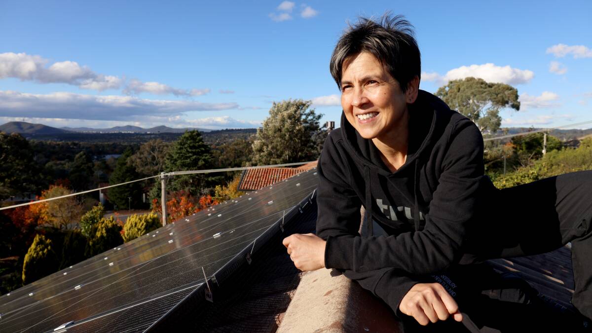 Sue Chong, on the roof of her Chapman home with solar panels, installed as part of an interest-free loan scheme. Picture: James Croucher