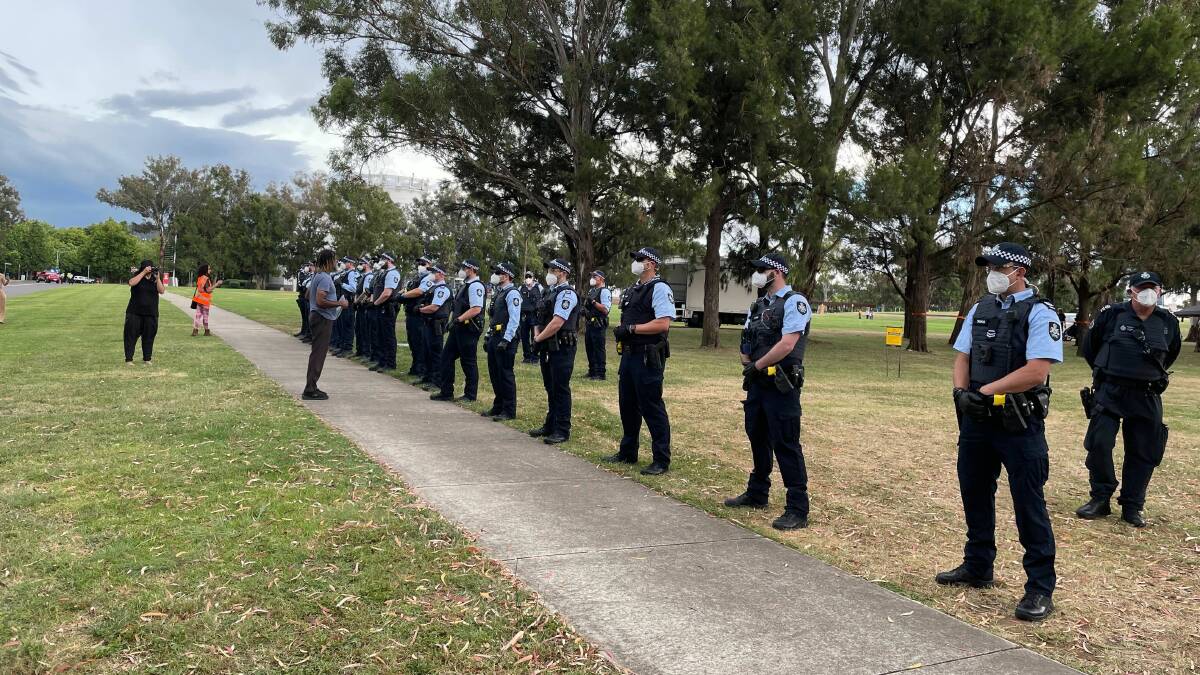 A line of police officers face off with a protester beside John Dunmore Lang Place off King Edward Terrace on Thursday afternoon. Picture: Miriam Webber