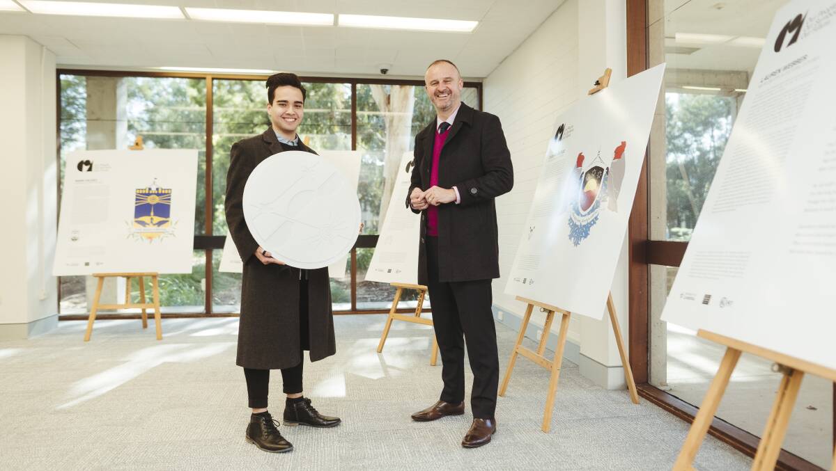 Masters student Liam Atkins, left, holds a 3D printed version of his coat of arms design to show ACT Chief Minister Andrew Barr at an exhibition of student work on Wednesday. Picture: Dion Georgopoulos
