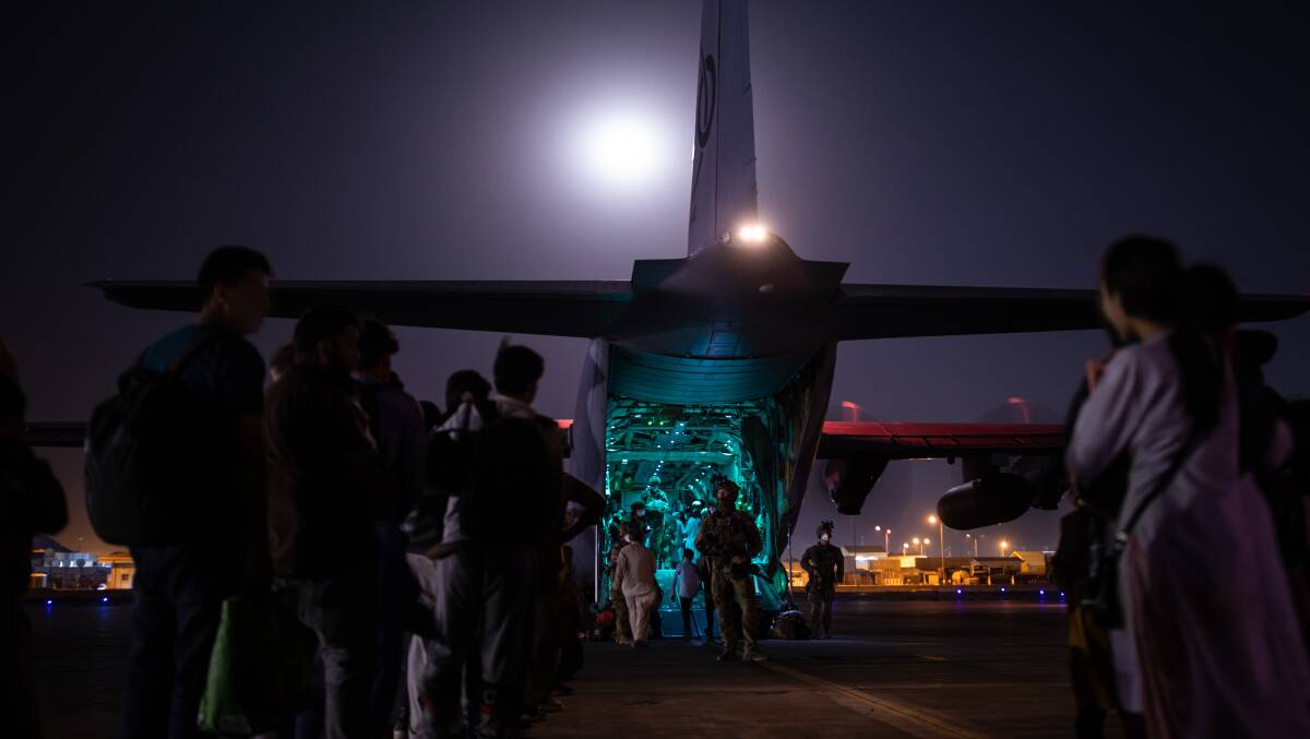 Australian citizens and visa holders form a line to board the Royal Australian Air Force C-130J Hercules as Australian military personnel provide security at Hamid Karzai International Airport. Picture: Department of Defence