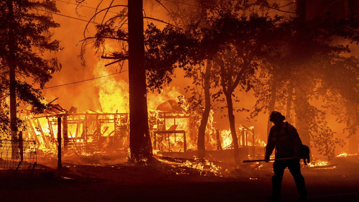 A firefighter passes a burning home as the Dixie Fire flares in California. Picture: AP