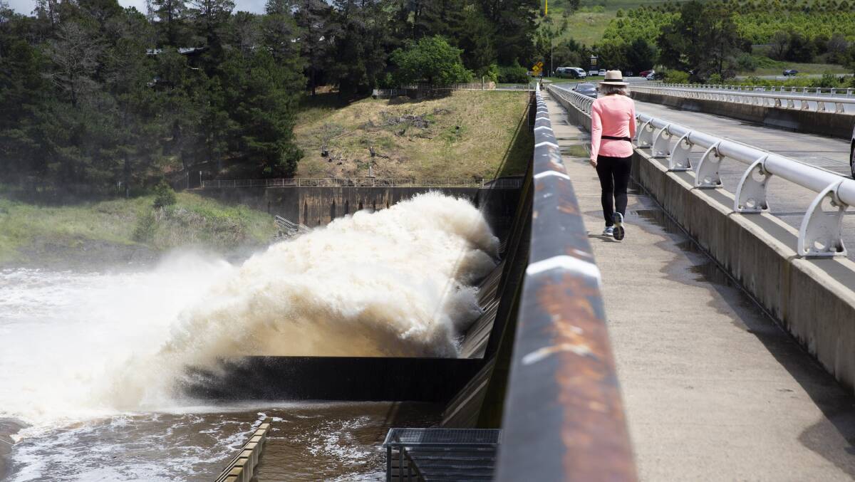Scrivener Dam releases water through its sluice gates on Sunday. More wet weather is predicted this week for Canberra. Picture: Dion Georgopoulos
