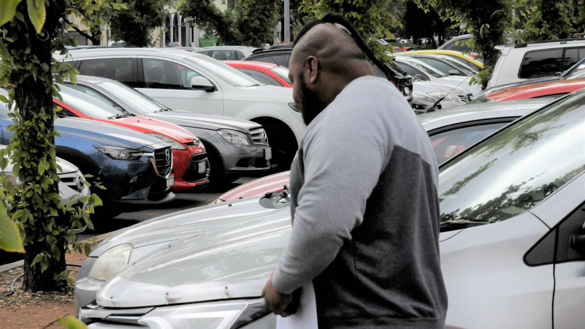 Osaiasi Kupu weaves through parked cars to avoid being photographed after a previous court appearance. Picture: Blake Foden