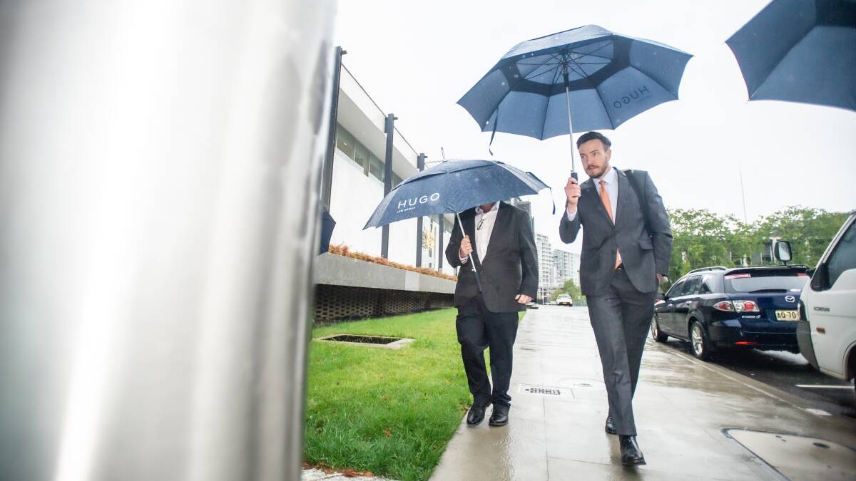 James Mussillon, left, shields his face with a Hugo Law Group umbrella as he arrives at court with solicitor Tom Taylor. Picture by Karleen Minney
