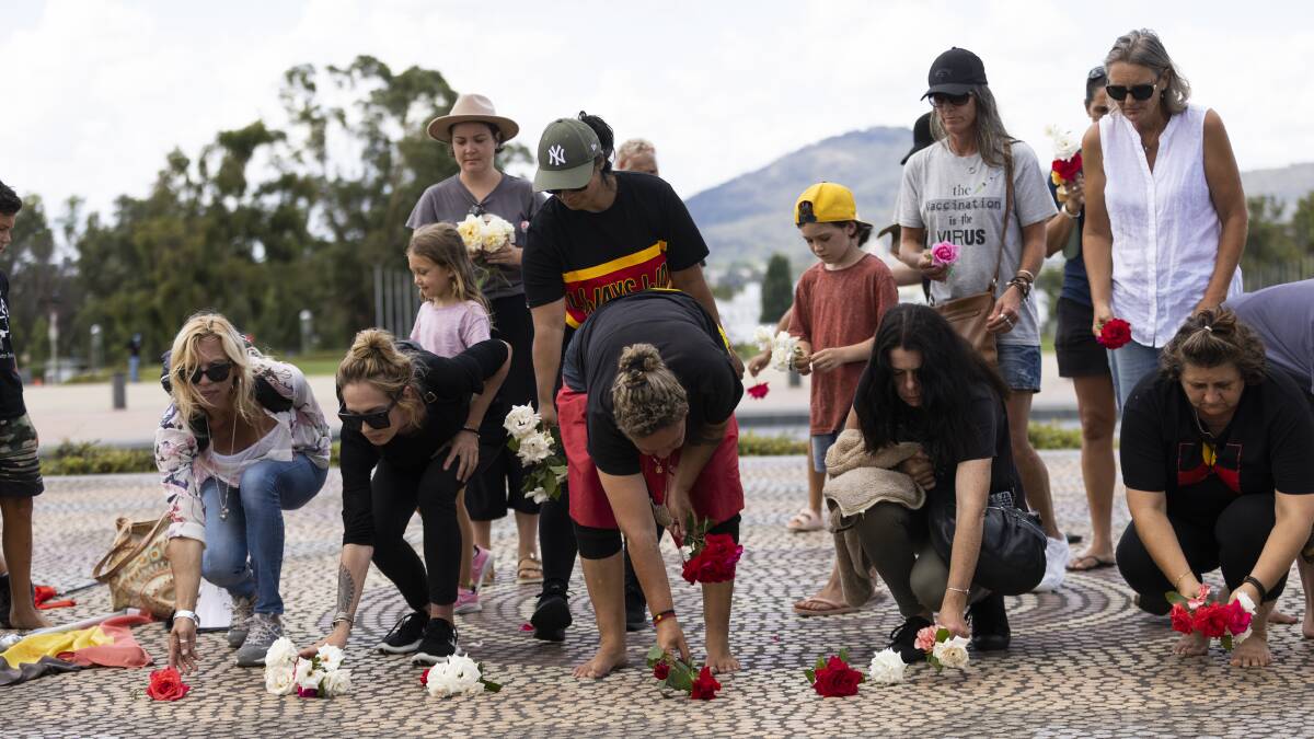 Women and children lay roses near the entrance to Parliament House on Saturday afternoon. Picture: Keegan Carroll