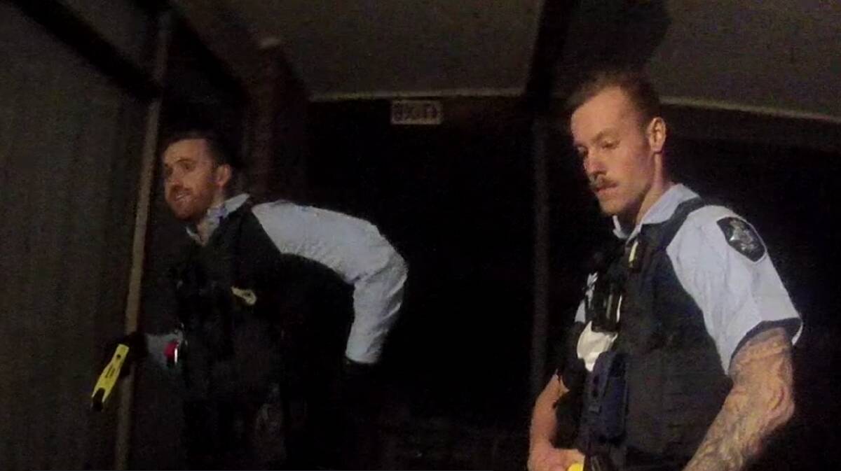 A police officer, left, holds his Taser prior to entering Luke Marsh's room.