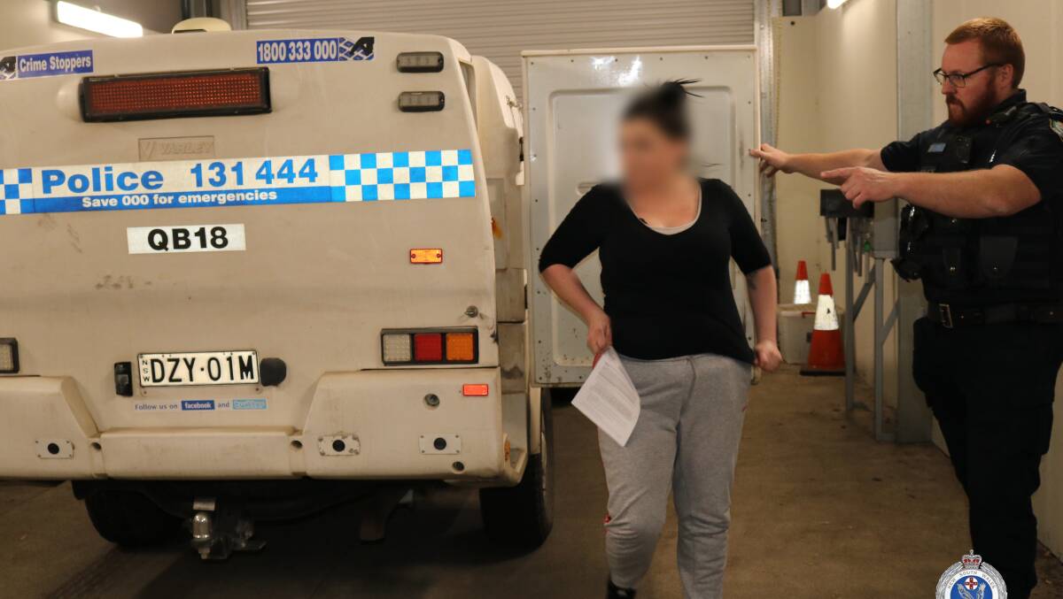 A woman is directed into Queanbeyan Police Station after her arrest. Picture: NSW Police