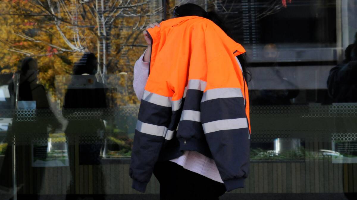 Loretta Tulikaki hides behind a high-visibility jacket as she leaves court on Tuesday. Picture: Blake Foden