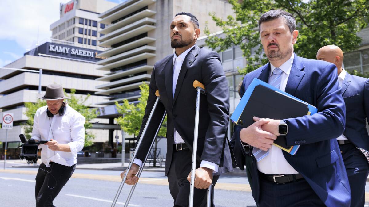 Nick Kyrgios, centre, walks to the ACT Magistrates Court with defence lawyer Michael Kukulies-Smith on Friday. Picture by Keegan Carroll