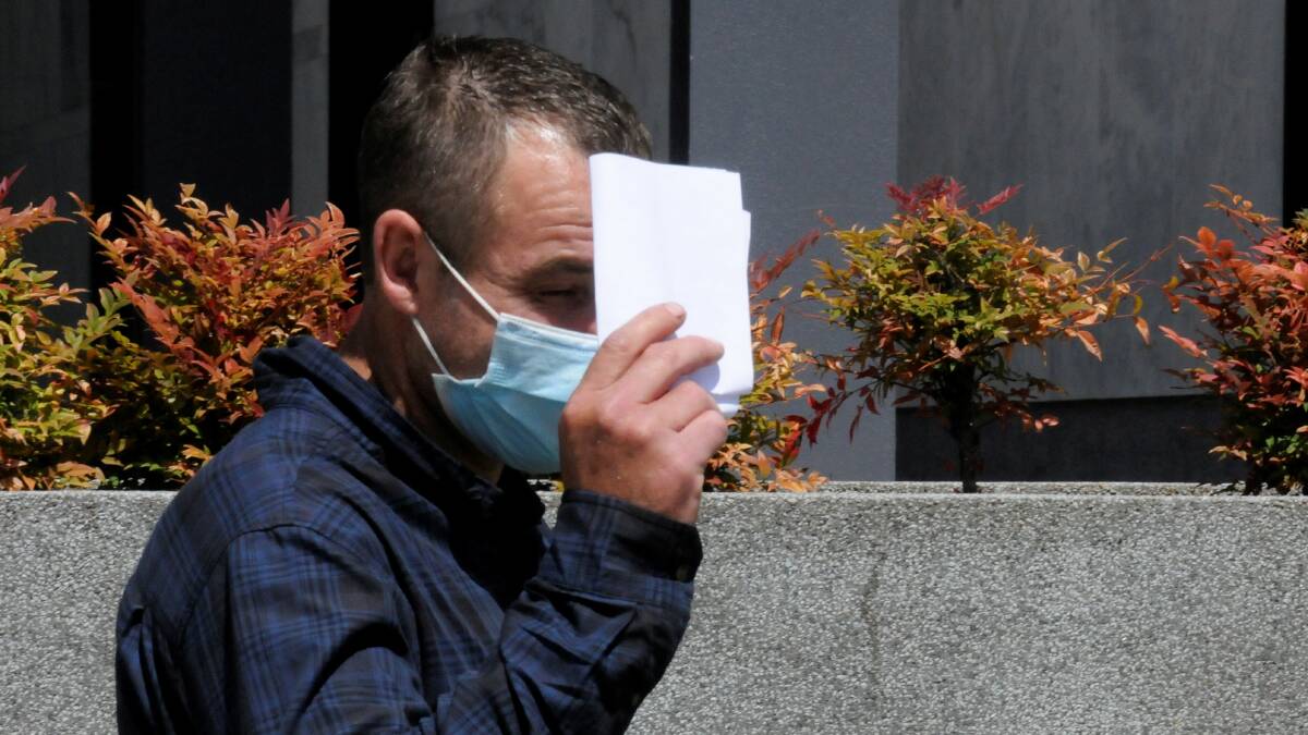 Jai Glover hides behind a piece of paper outside court in January. Picture: Blake Foden