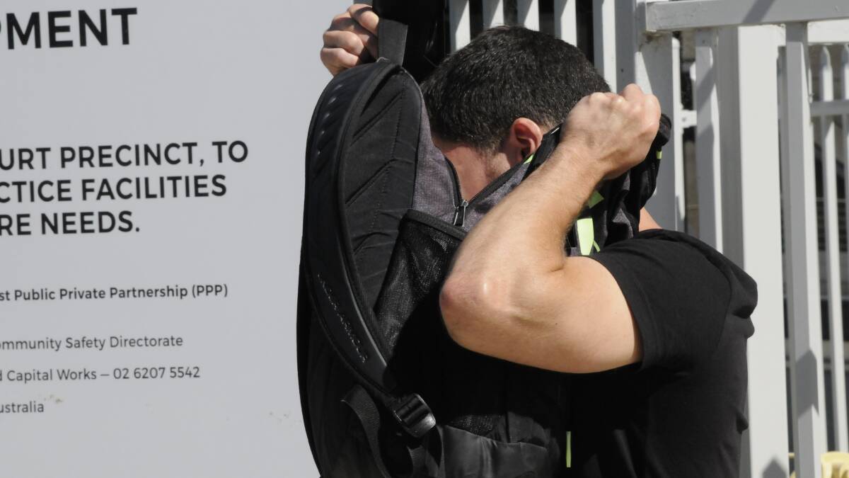 Timothy van Eyle hides behind a backpack outside court on Thursday. Picture: Blake Foden