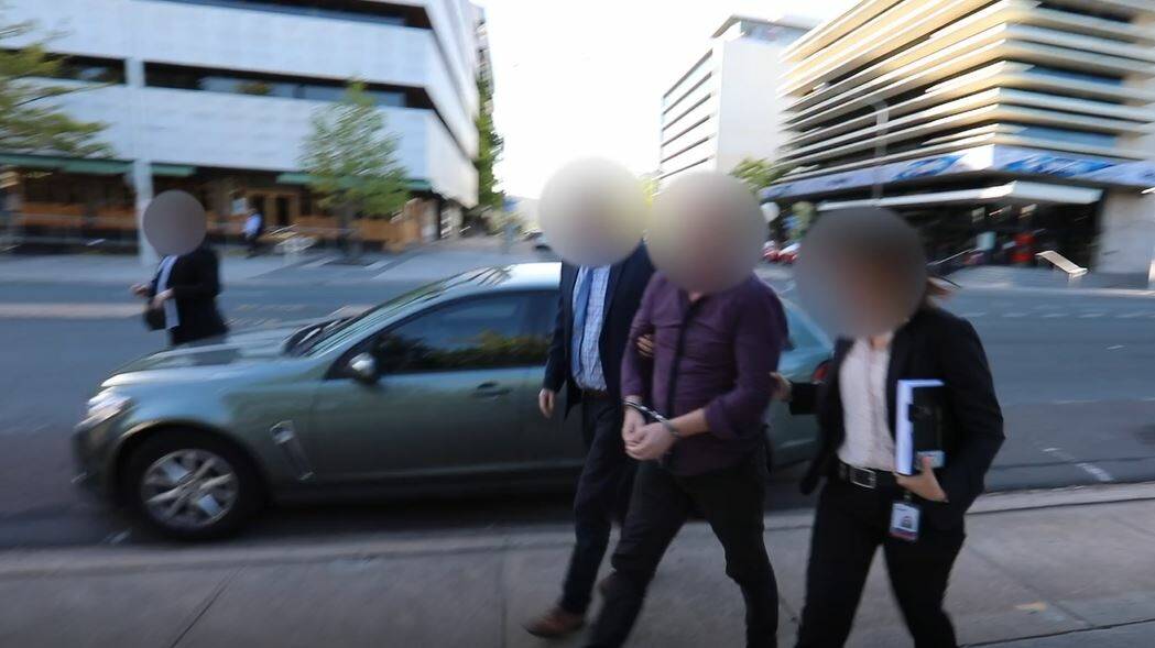Detectives lead Bradley Grey, centre, into City Police Station following his arrest. Picture: ACT Policing