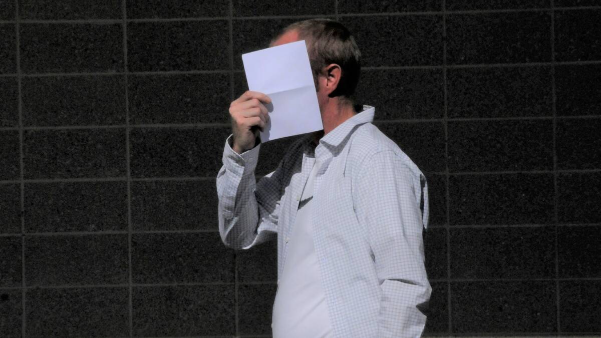 Adam Chavasse hides behind a sheet of paper outside court. Picture: Blake Foden