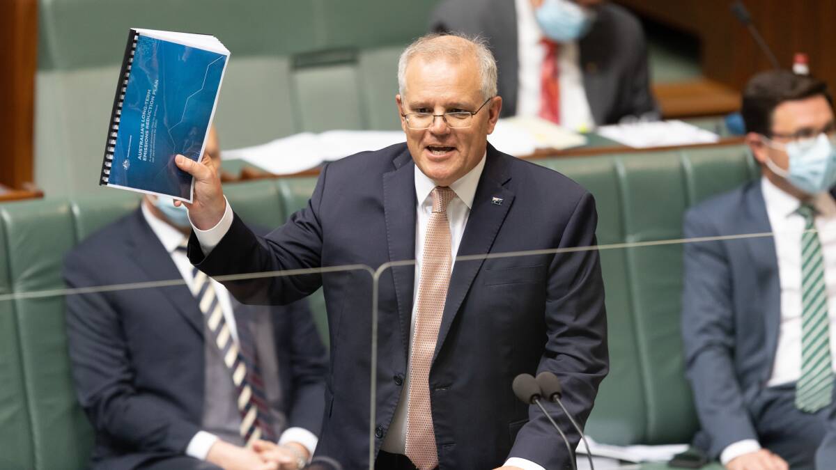Prime Minister Scott Morrison holds a copy of the government's emissions plan. Picture: Sitthixay Ditthavong