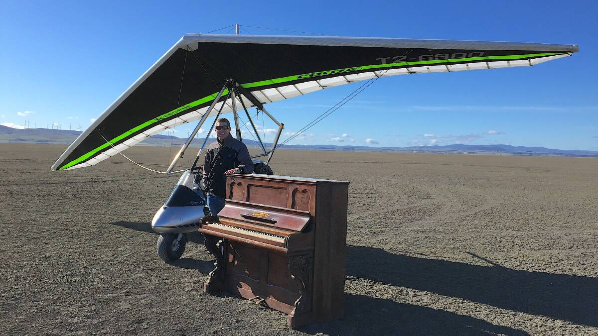 Microlight pilot Andrew Luton with the out-of-place piano he spotted this week in the middle of Lake George. Picture: Andrew Luton