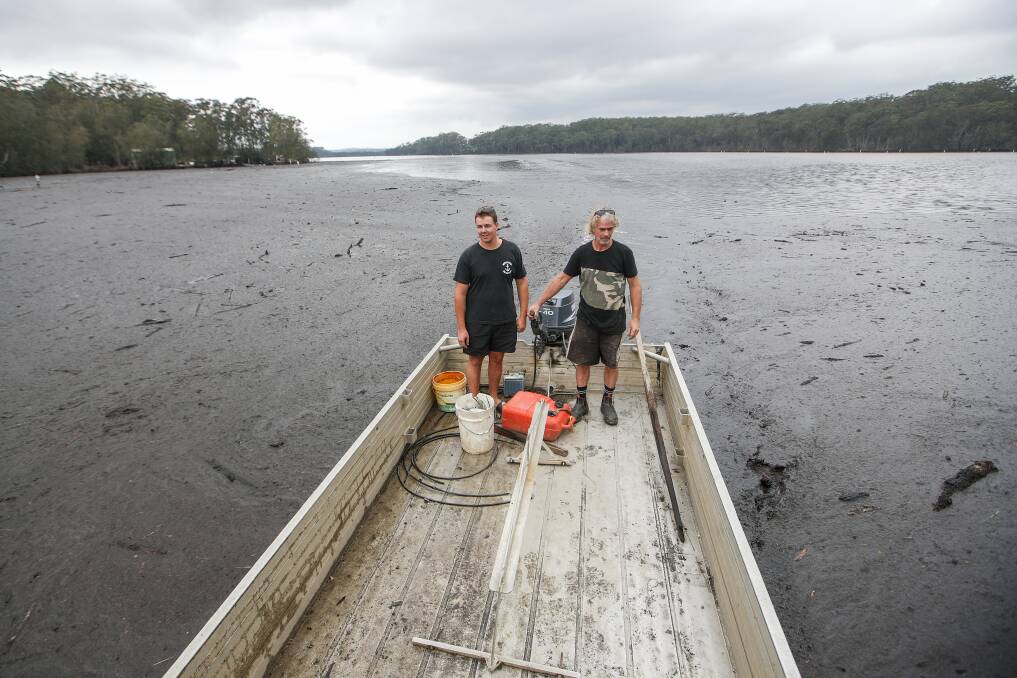 Tyron and Anthony Brice venture through the muck on the Tuross River to assess their oyster leases. Picture: Adam McLean