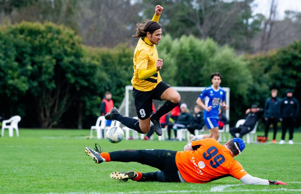 Tigers FC's Nikolas Popovich leaps over Canberra Olympic goalkeeper Angelo Konstantinou last week. Picture: Elesa Kurtz