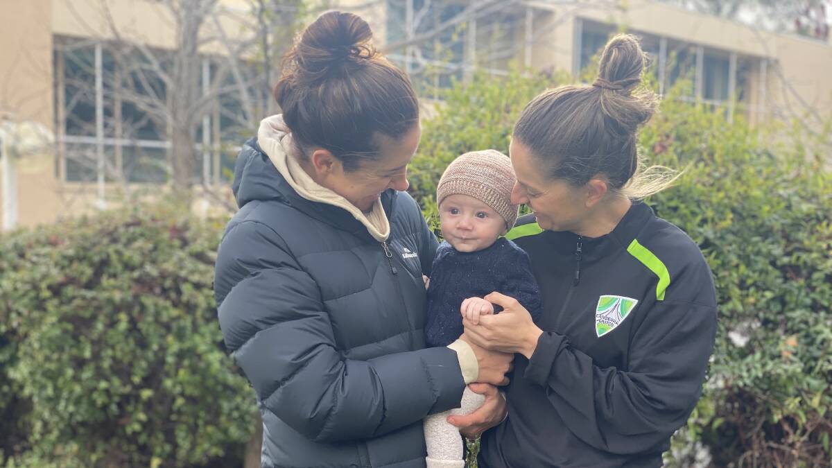 Canberra United's Ellie Brush (right) with two of the things driving her decision to return to the capital. Her wife Kristy Sutcliffe, and five-month-old son Leo.