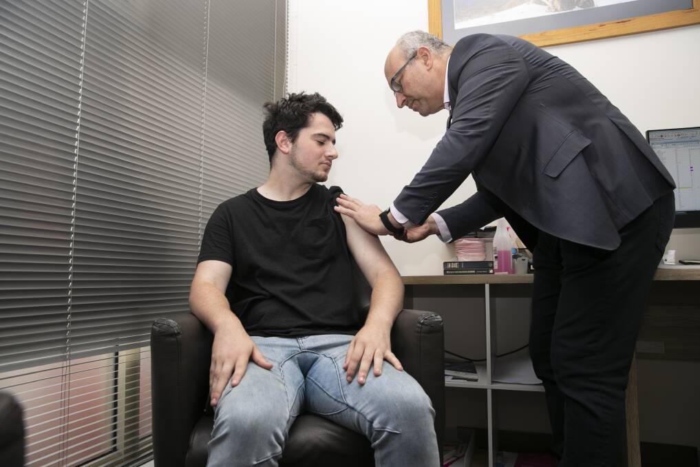 Dr Antonio Di Dio giving Matthew Di Dio one of hundreds of flu jabs doled out at his practice on Friday. Picture: Keegan Carroll